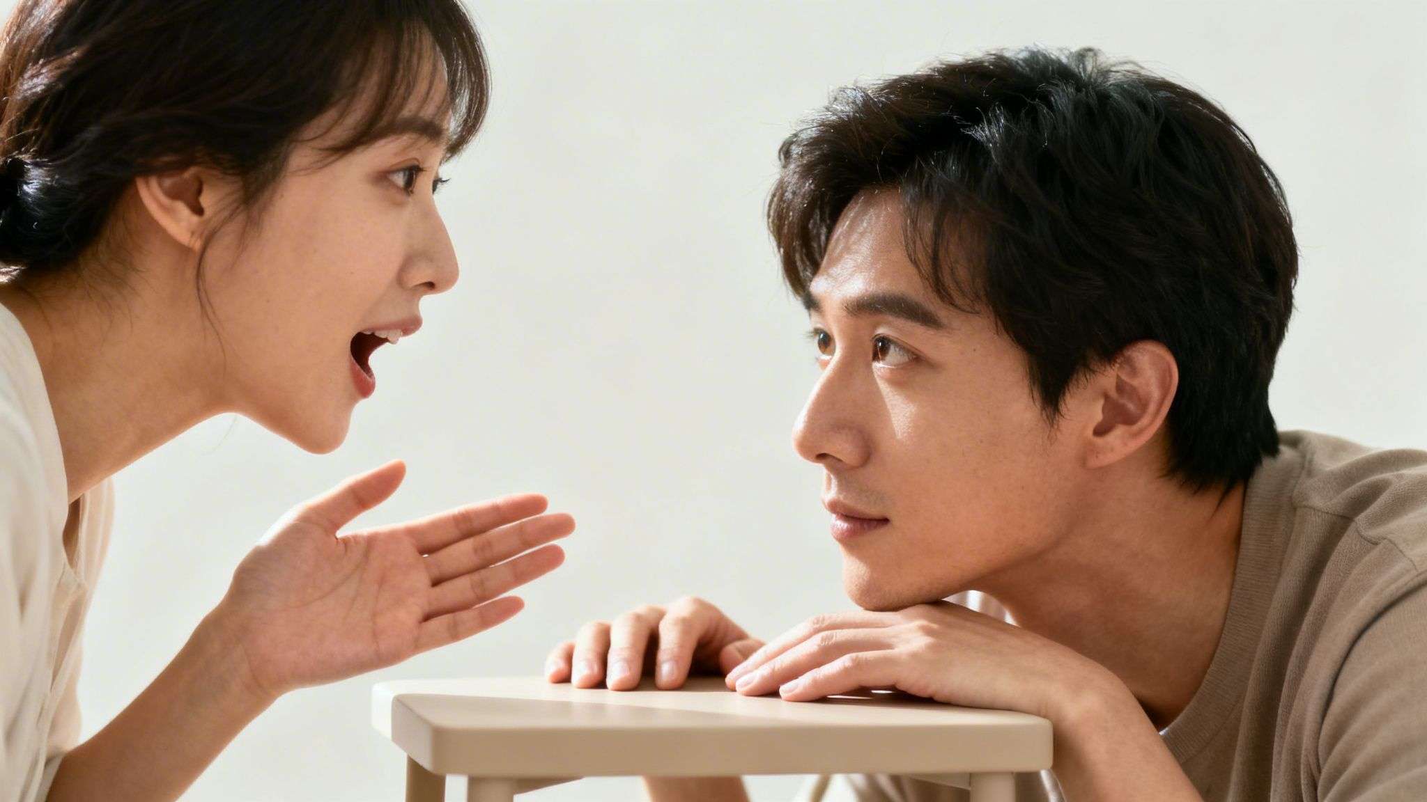 A woman speaks animatedly to a man leaning on a table, engaged in a serious conversation.