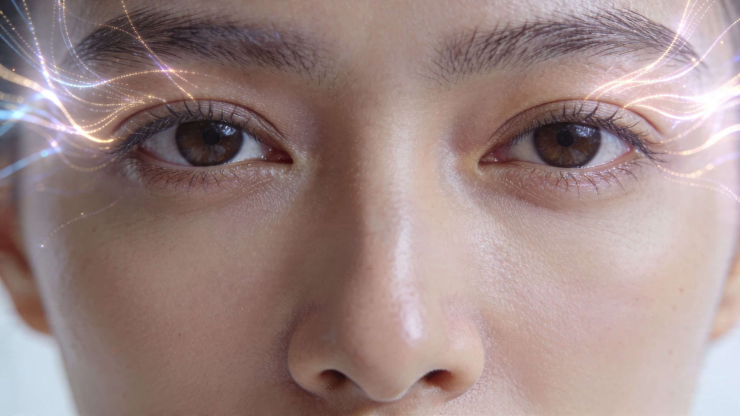 Close up of a person eyes looking forward with glowing digital lines emanating from their brows.