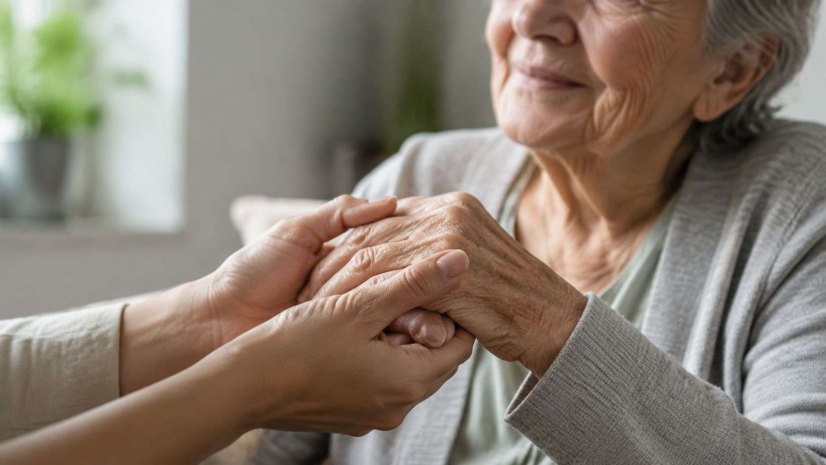 A close-up of a person holding the wrinkled hands of an elderly woman as a gesture of support.