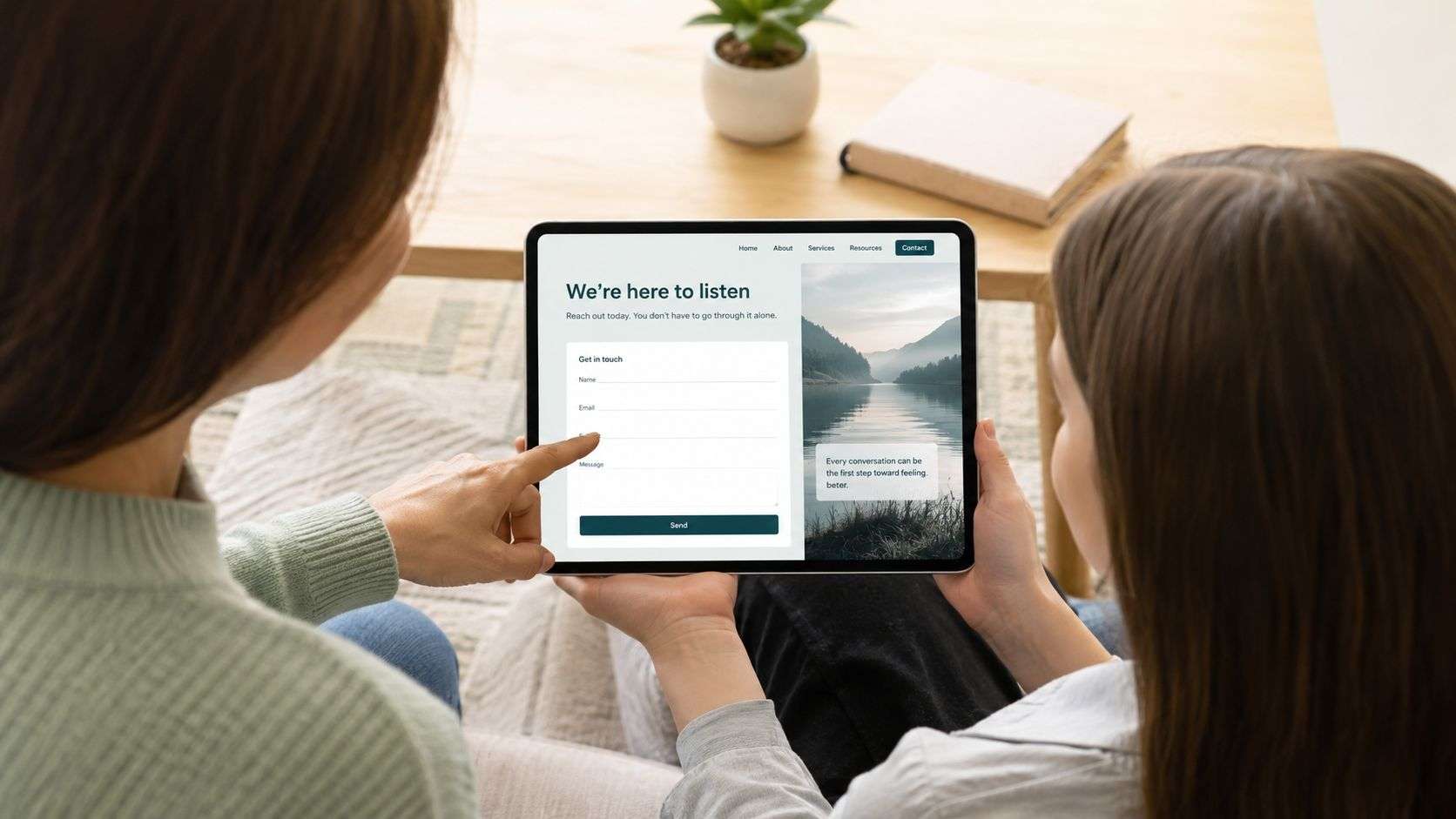 A mother and her teenage daughter looking at a mental health counseling contact form on a tablet.